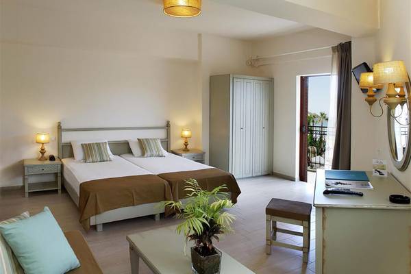 Schlafzimmer im Almyrida Beach Hotel mit zwei Betten, Nachttischen, Deckenlampen und einem Kleiderschrank.
