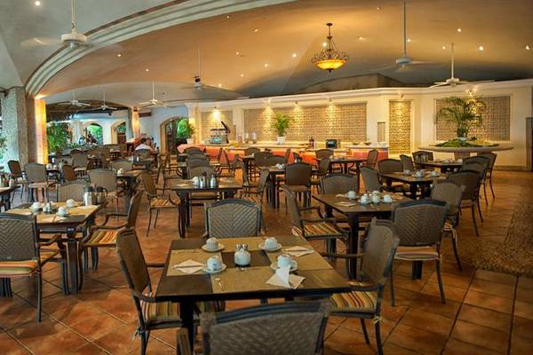 Innenansicht des Restaurants im Tamarindo Diria Beach Resort mit runden Tischen und Stühlen.
