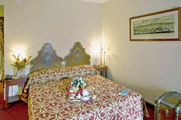 Doppelbett im Palazzo Marcello Hotel Al Sole mit Blumen, Frühstückstablett und Gemälde an der Wand.