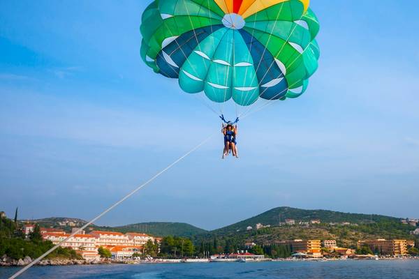 Zwei Personen im Parasailing über dem Meer vor Remisens Hotel Albatros