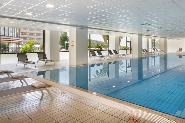 Ein großer Innenpool im Remisens Hotel Albatros mit Lounge-Stühlen und Handläufen.