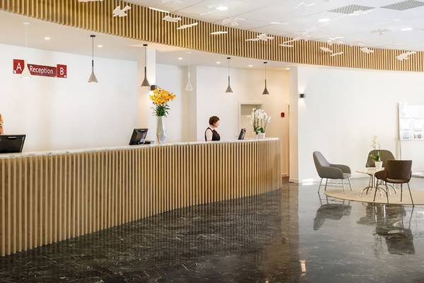 Rezeption des Remisens Hotel Albatros mit zwei Angestellten, Blumen und modernen Möbeln.