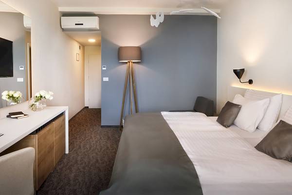 Ein stilvolles Hotelzimmer im Remisens Hotel Albatros mit einem Doppelbett, Nachttisch und Fernseher.