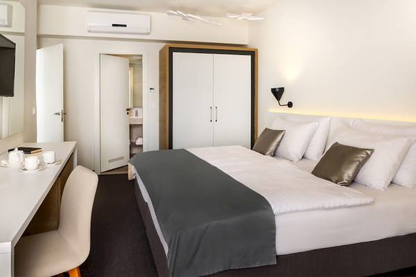 Schlafzimmer im Remisens Hotel Albatros mit Doppelbett, Fernseher und Schreibtisch.