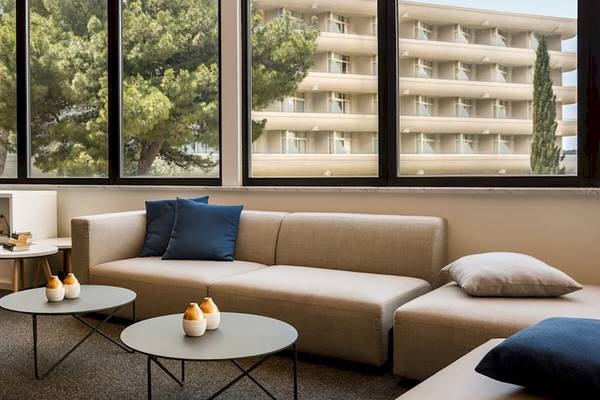 Remisens Hotel Albatros Lobby mit Sofas, Tischen und Büchern in der Nähe eines Fensters.