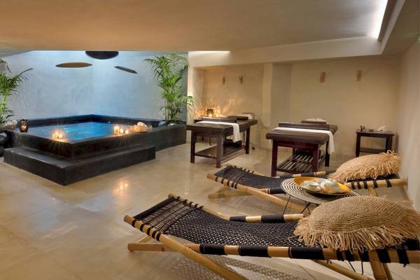 Massageraum im Saint John Hotel Villas & Spa mit Jacuzzi, Liegestühlen und Pflanzen.