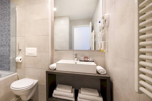 Badezimmer im Remisens Hotel Albatros mit Badewanne, Toilette, Waschbecken und Handtüchern.