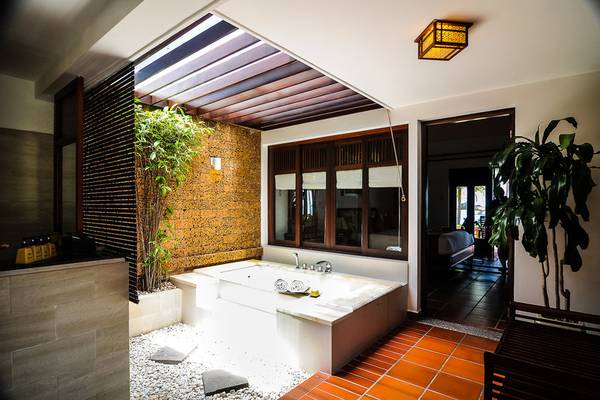 Badezimmer des Palm Garden Beach Resort Hoi An mit Badewanne und Fenstern.