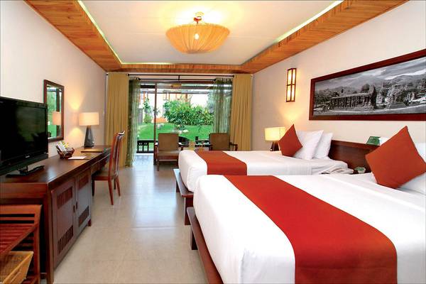 Doppelzimmer im Palm Garden Beach Resort Hoi An mit zwei Betten, Fernseher, Schreibtisch und Gartenblick.