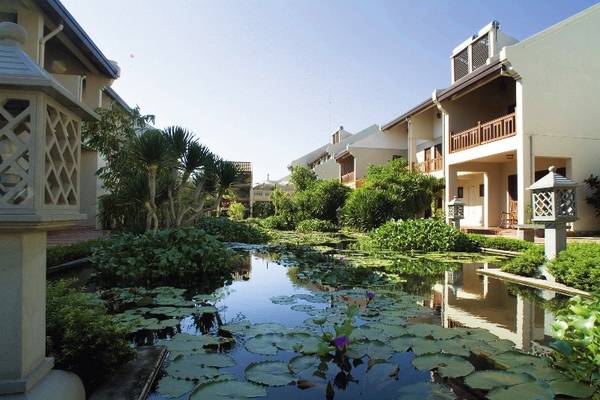 Außenansicht des Palm Garden Beach Resort Hoi An mit einem Garten und einem Seerosenteich.