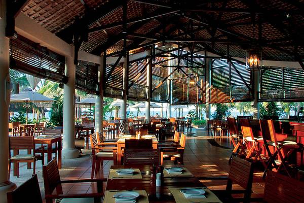 Innenansicht des Restaurants im Palm Garden Beach Resort mit vielen Holztischen und Stühlen.