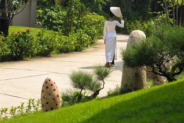 Frau im weißen Kleid geht auf einem Weg im Palm Garden Beach Resort Hoi An
