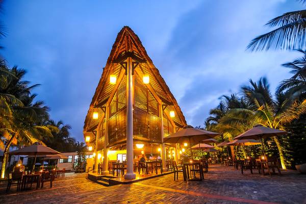 Außenterrasse des Palm Garden Beach Resort bei Nacht mit leuchtenden Lampen und Tischen