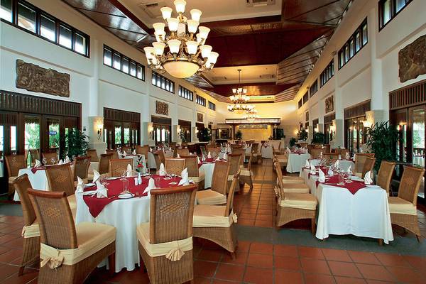 Innenansicht des Restaurants im Palm Garden Beach Resort Hoi An mit gedeckten Tischen und Stühlen.