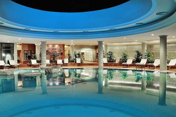 Innenpool des Gloria Verde Resorts mit blauer Beleuchtung und weißen Liegestühlen.