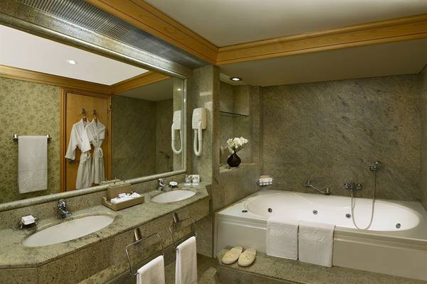 Badezimmer im Gloria Verde Resort mit Badewanne, Spiegel und zwei Waschbecken.