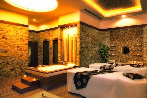 Spa-Bereich im Gloria Verde Resort mit Badewanne, Massagebetten und Steinwänden.