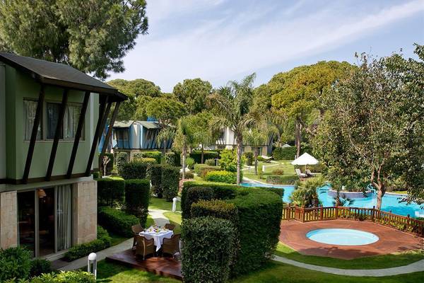 Außenbereich des Gloria Verde Resorts mit einem Swimmingpool und Tisch für das Frühstück