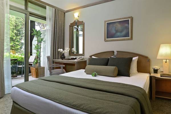 Hotelzimmer im Gloria Verde Resort mit Doppelbett, Schreibtisch und Gartenblick.