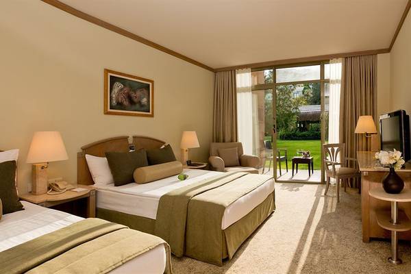 Doppelzimmer im Gloria Verde Resort mit zwei Betten, großer Fensterfront und Gartenblick.