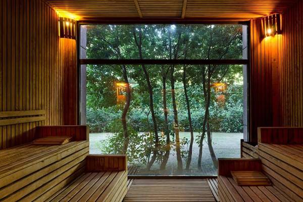 Innenansicht des Saunaraums im Gloria Verde Resort mit großen Fenstern und Holzwänden.