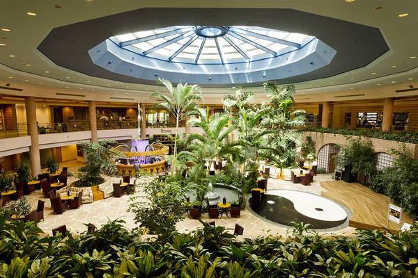 Innenbereich des Gloria Verde Resorts mit Atrium, Pflanzen und Sitzbereichen.