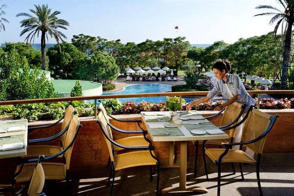 Eine Mitarbeiterin des Gloria Verde Resorts bereitet einen Tisch auf der Terrasse vor.