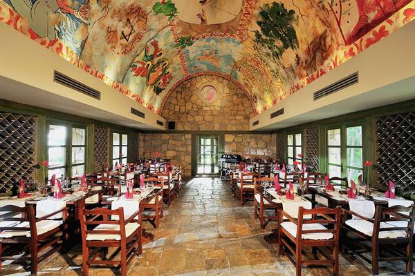 Das Interieur des Gloria Verde Resorts zeigt einen steinernen Boden und eine Decke mit farbenfrohen Wandgemälden.
