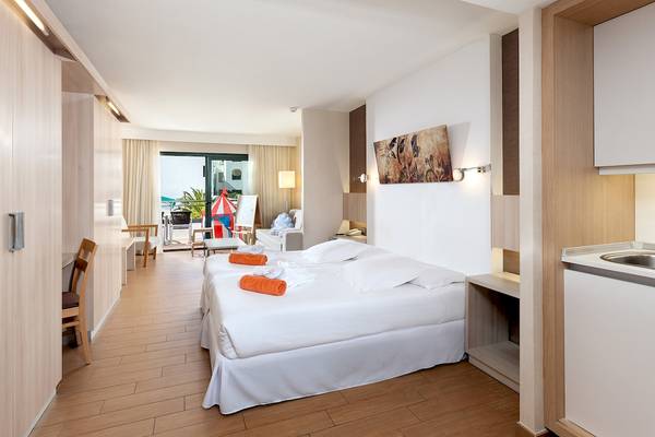 Doppelbett mit weißen Laken und orangenen Handtüchern im Schlafzimmer des Be Live Experience Lanzarote Beach Hotels.