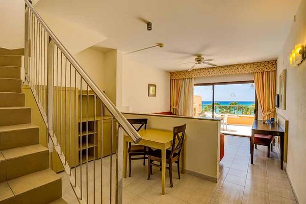 Innenbereich des SBH Taro Beach Hotels mit Tisch, Stühlen und Blick auf das Meer.