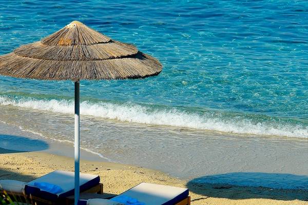 Ein Strand mit einem Sonnenschirm und zwei Liegen am Meer