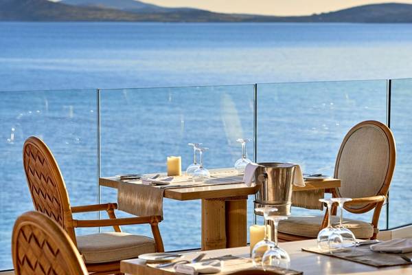 Terrasse des Saint John Hotel Villas & Spa mit Blick auf das Meer und zwei gedeckten Tischen.
