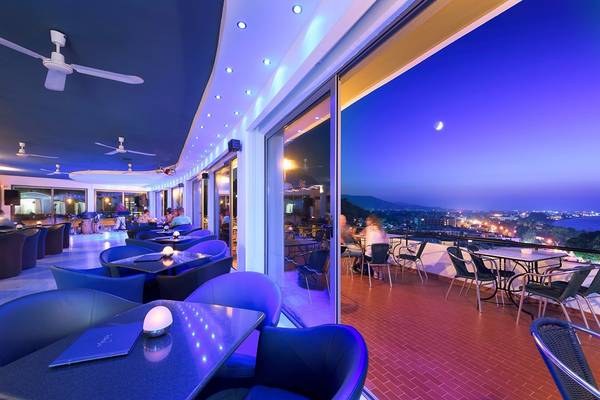Dachlounge des Olympic Palace Resorts mit blauen Möbeln und Nachtansicht.