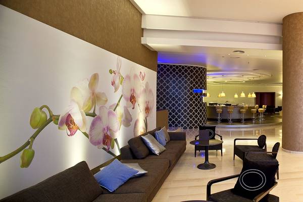 Lobby des Olympic Palace Resorts mit Wandbild von Orchideen, Barbereich und Sitzgelegenheiten.