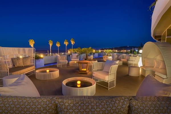 Außenbereich des Olympic Palace Resorts bei Nacht mit beleuchteten Möbeln und Pflanzen.