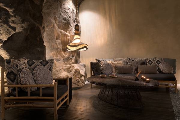 Lounge-Bereich im Olympic Palace Resort mit Steinwand, Sofas, Tischen und Lampen.