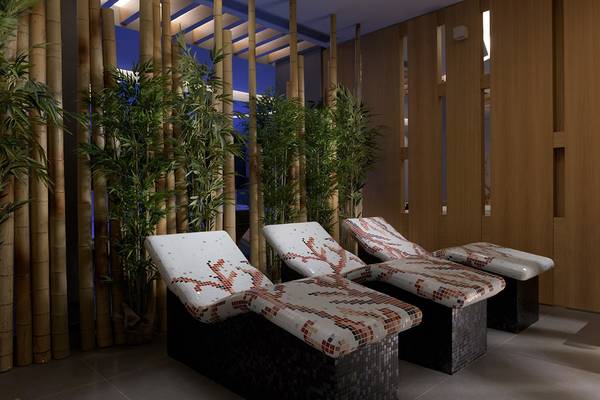 Loungebereich im Olympic Palace Resort mit drei Liegen und Bambuspflanzen.