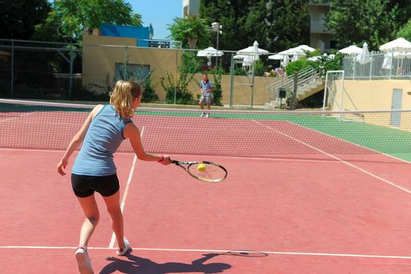 Tennisspielerin im Olympic Palace Resort schlägt den Ball über das Netz.
