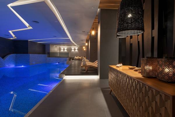 Innenpool im Olympic Palace Resort mit blauer Beleuchtung und Holzlounges