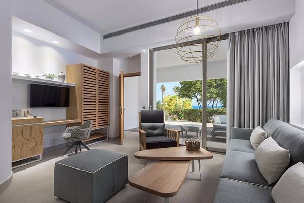 Wohnbereich des Olympic Palace Resorts mit Sofa, Tisch und Blick auf den Garten.