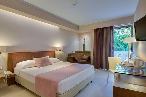 Schlafzimmer im Olympic Palace Resort Hotel mit Doppelbett, Nachttisch, Fernseher und Balkon.