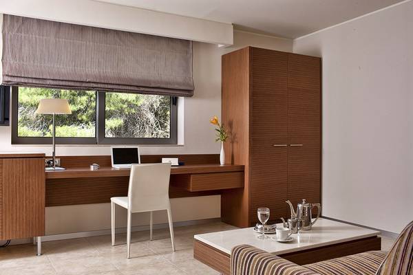 Arbeitsplatz im Zimmer des Olympic Palace Resort mit Schreibtisch, Laptop, Stuhl und Lampe.