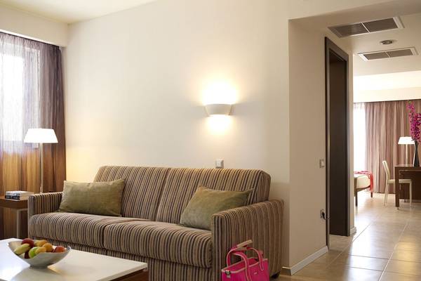 Wohnzimmer im Olympic Palace Resort mit Sofa, Tisch und Dekoration.