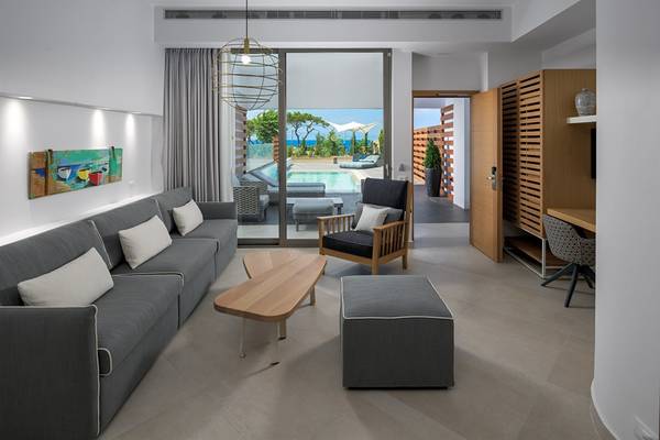 Modernes Wohnzimmer des Olympic Palace Resorts mit Aussicht auf den Pool.