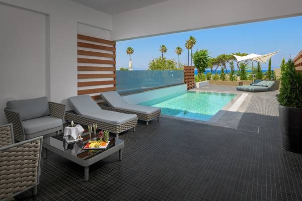 Pool-Terrasse im Olympic Palace Resort mit Sonnenliegen und einem Blick auf das Meer.