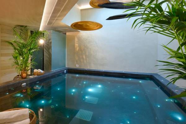 Innenpool im Saint John Hotel Villas & Spa mit blauen Lichtern und Pflanzen.