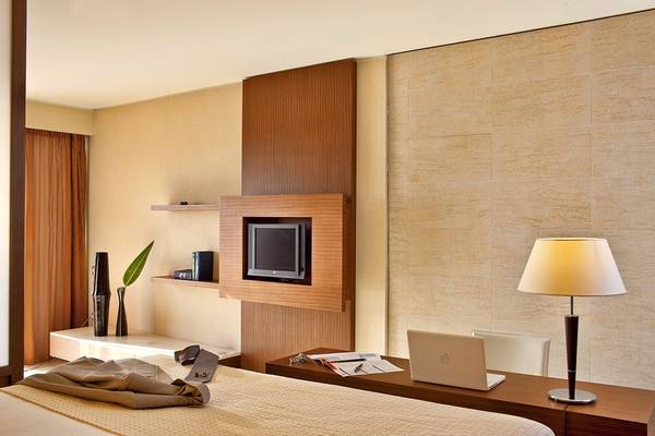 Innenansicht eines Hotelzimmers im Olympic Palace Resort mit Bett, Schreibtisch, Laptop, Lampe und Fernseher.