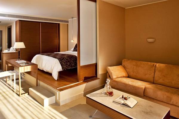 Innenansicht der Hotelsuite im Olympic Palace Resort mit Bett, Schreibtisch und Sofa.