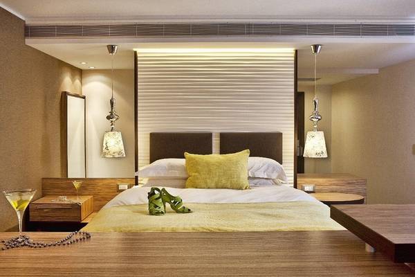 Schlafzimmer im Olympic Palace Resort mit einem Bett, gelben Kissen und grünen Schuhen auf dem Bett.