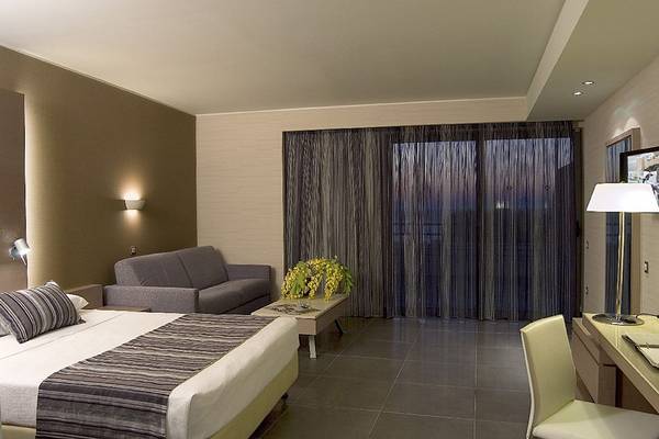 Hotelzimmer im Olympic Palace Resort mit Bett, Sofa, Schreibtisch und Lampe.